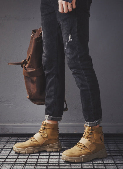 Stylish winter men's boots in tan, paired with black denim and a brown backpack, perfect for fashion-forward looks.